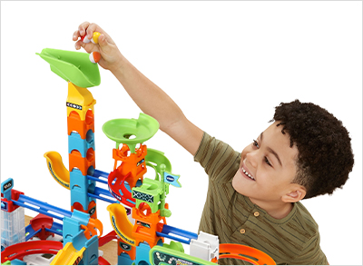 Child dropping several marbles into the Green Fill & Tip Barrel to send them down the track.